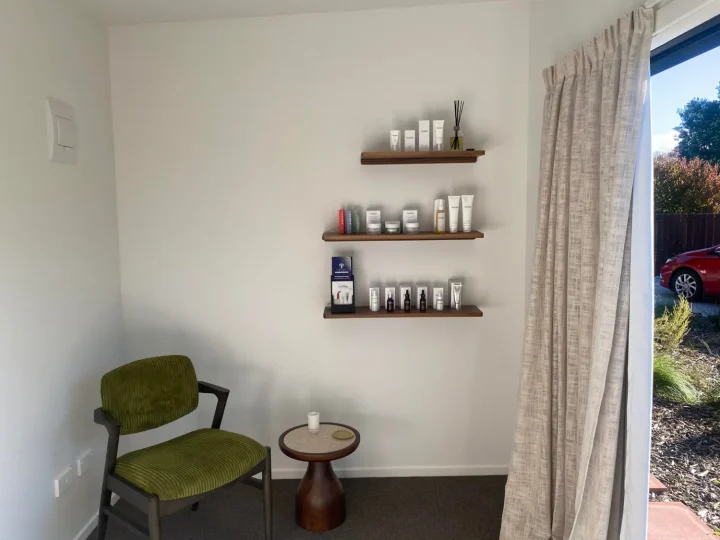 Cabin set up as a skincare treatment room, with product shelves, a chair and a side table