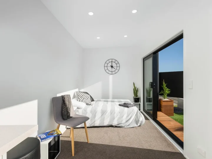 Cabin furnished as a bedroom, with a bed, an armchair and a wall clock