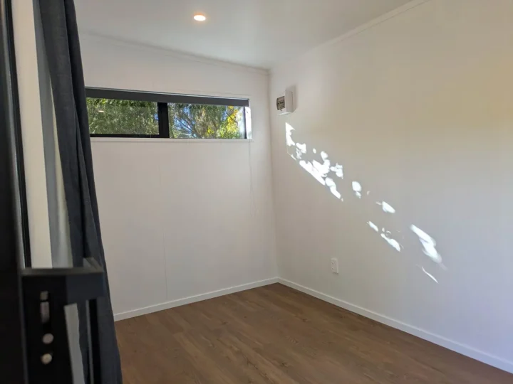 Sunlit cabin interior with vinyl plank flooring, white walls and a high window