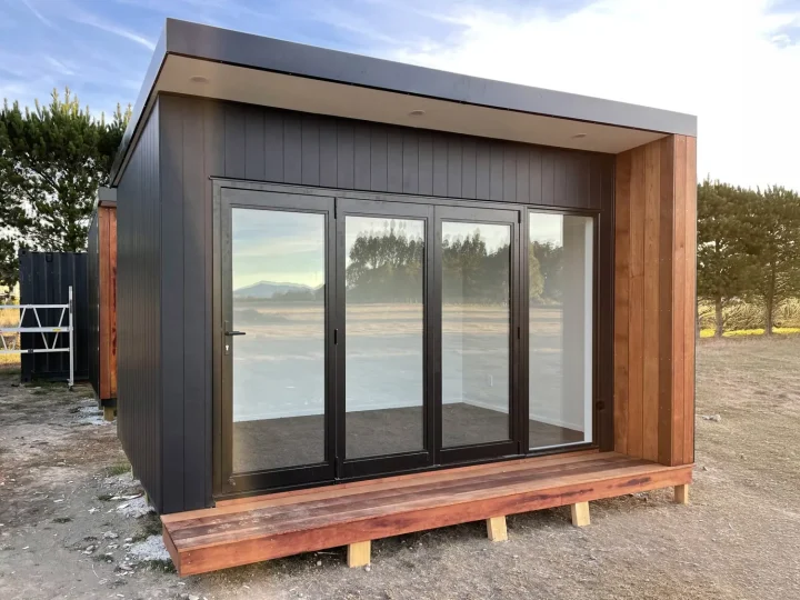 Black cabin with four glazed doors, a kwila surround and deck