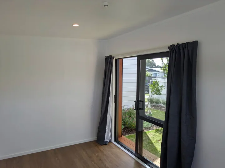 Cabin interior with vinyl plank flooring and dark curtains at the glazed door