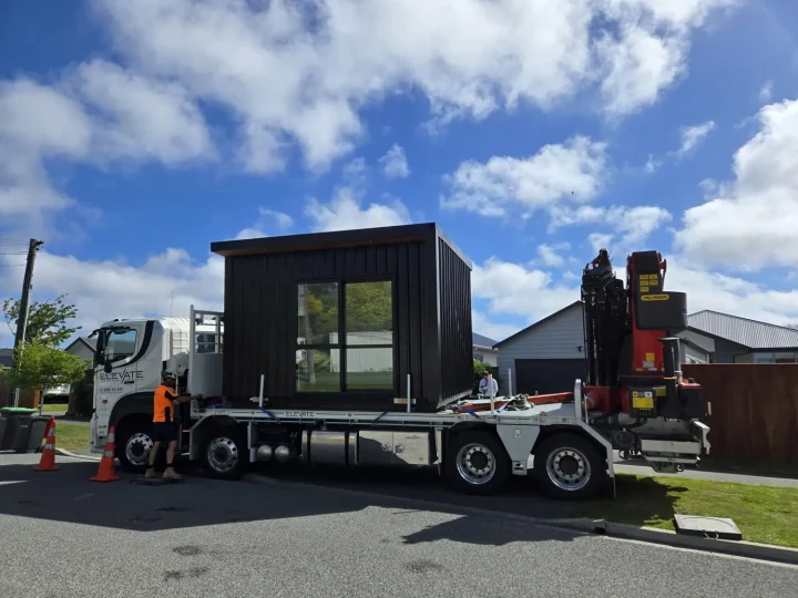 A crane truck on a residential street with a black cabin on its deck