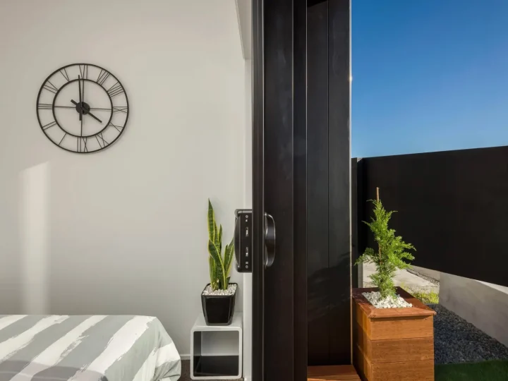 Bedroom corner of a cabin with a wall clock, looking out through the open door