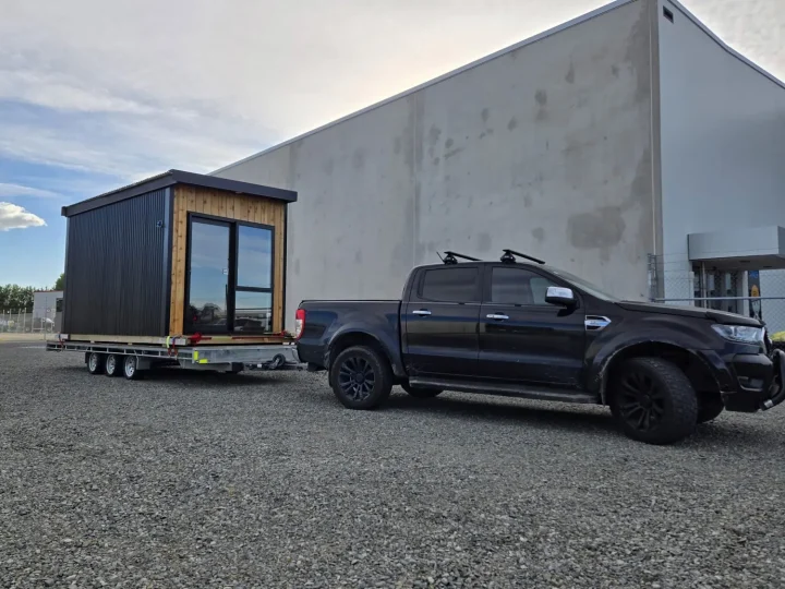 A black cabin on a trailer behind the Cube Cabins ute