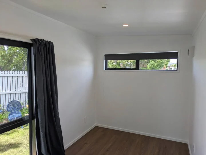 Cabin interior with a high window, vinyl plank flooring and dark curtains