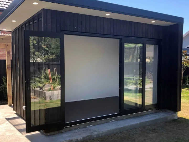 Black cabin with its wide sliding doors open and soffit lights on