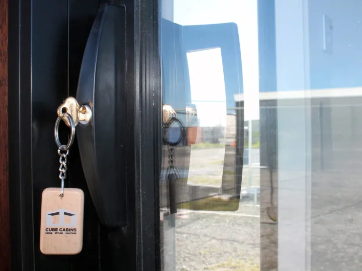 A Cube Cabins key tag hanging in the lock of a glazed door