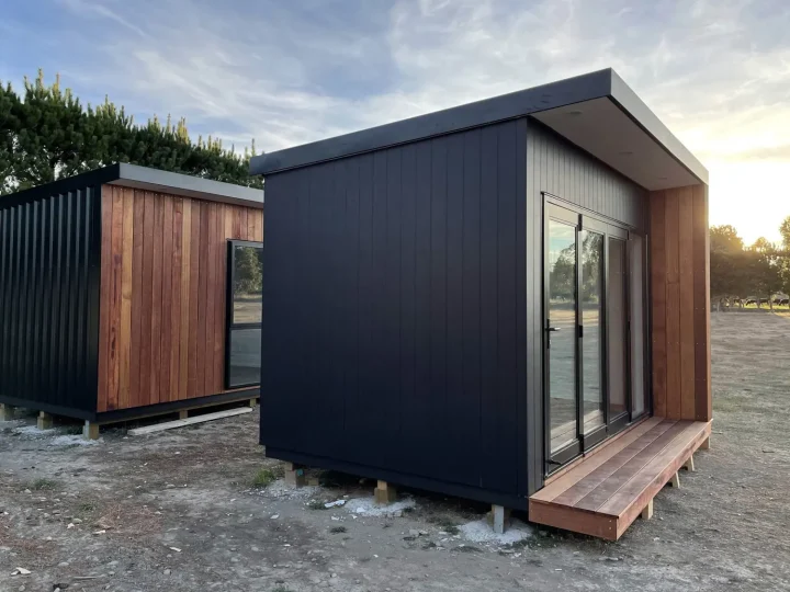 Two cabins side by side, one black with a kwila surround and one clad in kwila