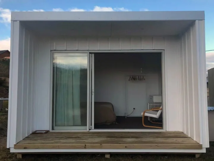 White cabin with its sliding door open and a chair inside